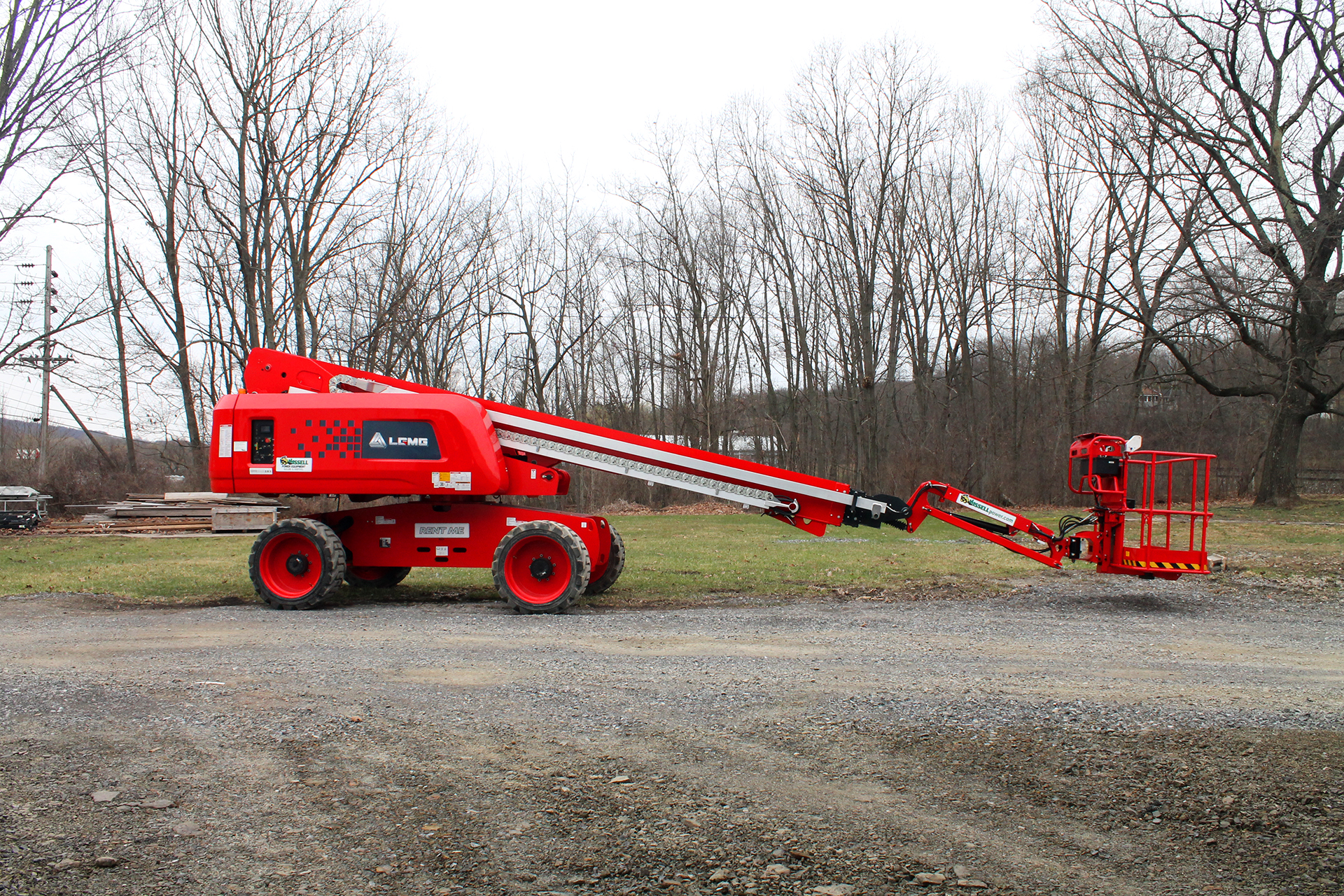 A red, LGMG lift in a field with its telescopic arm down