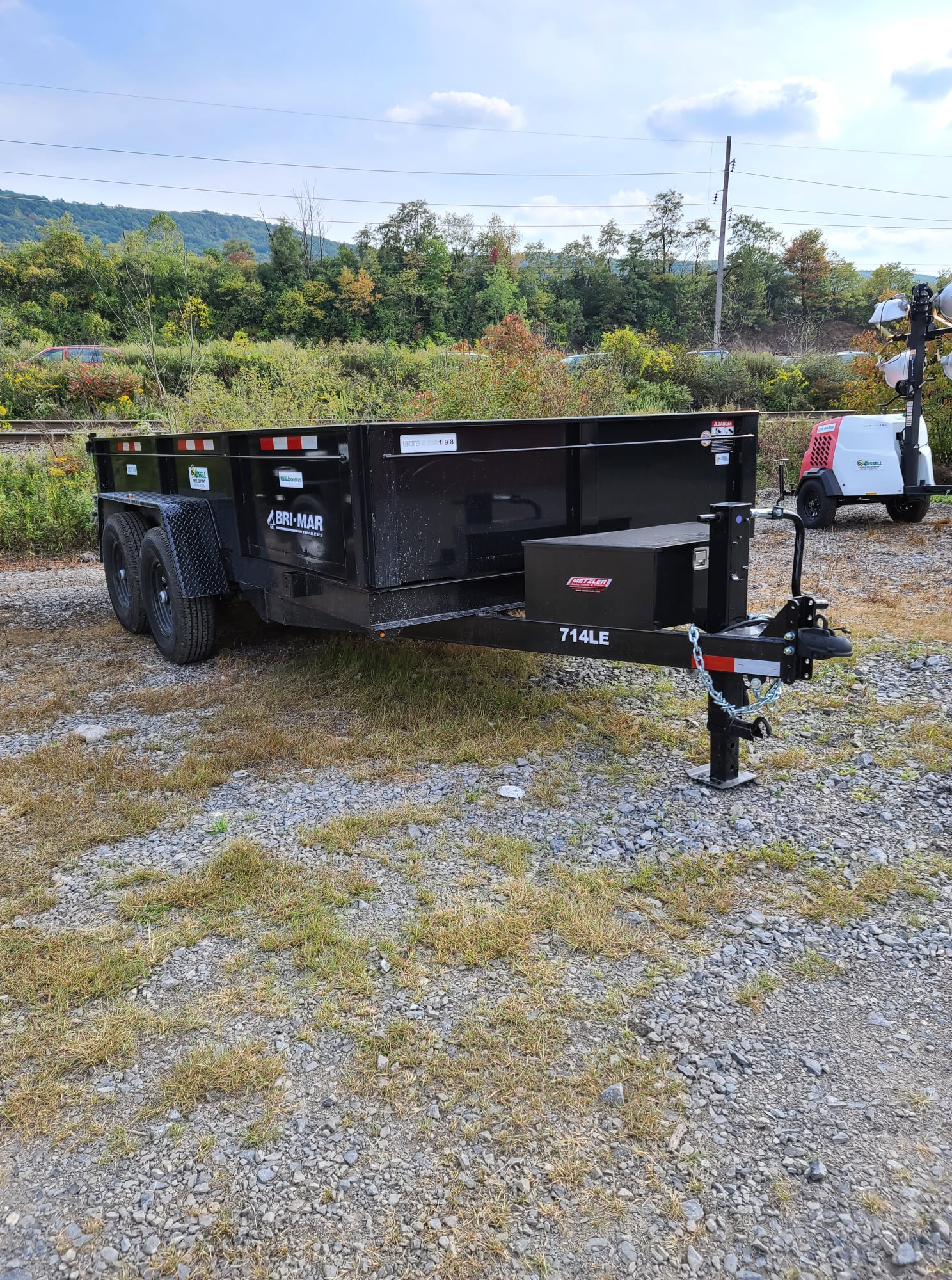 A dump trailer with two wheels on each side and a cool black finish.