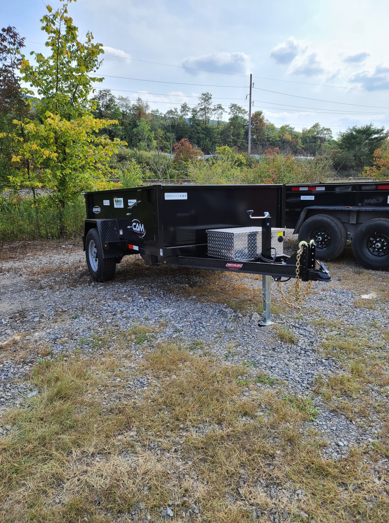 A dump trailer with a towable hitch, held up by the built in jack!